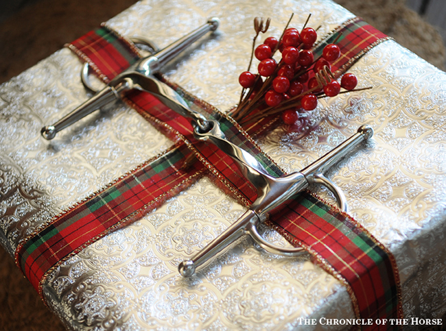 A snaffle bit, ribbon, and berries accent this equestrian present