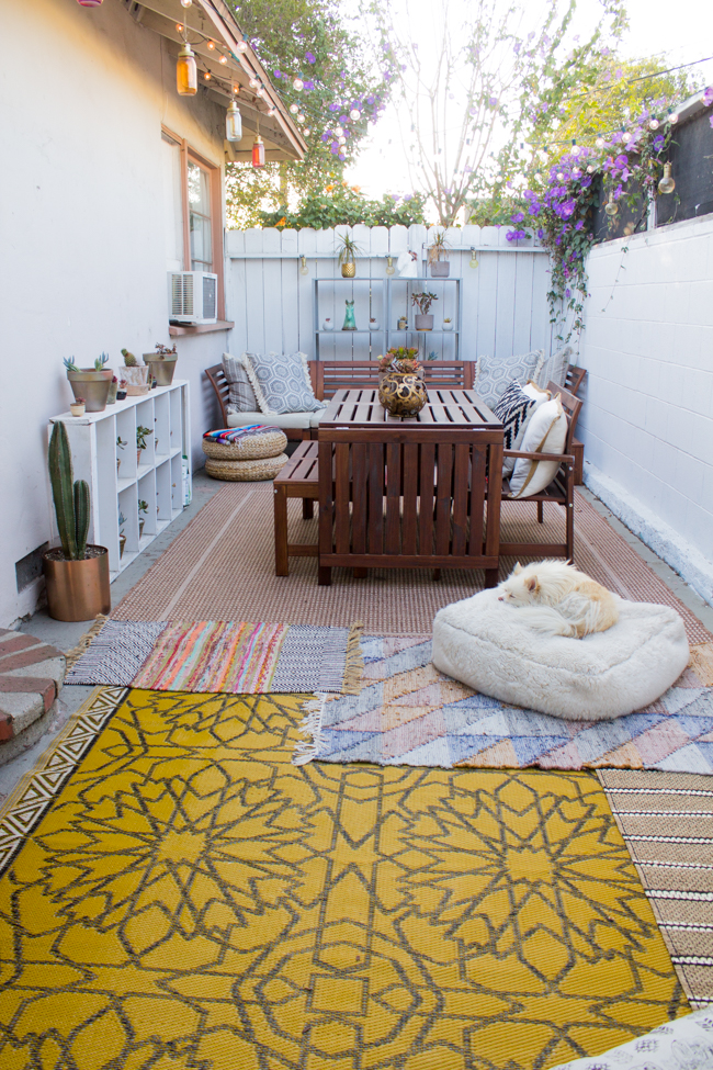 Bohemian outdoor patio area in Los Angeles with layered rugs 