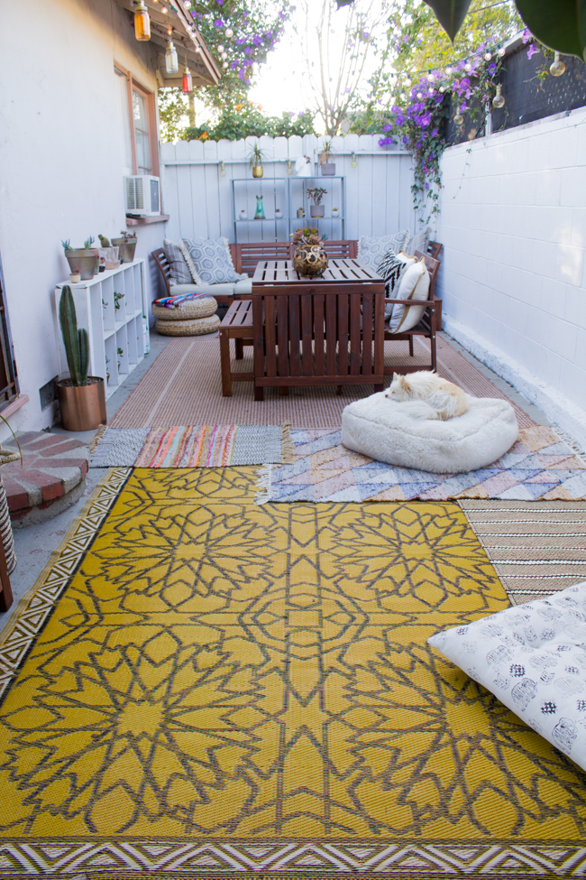bohemian patio with rugs, a couch, and dining table. 
