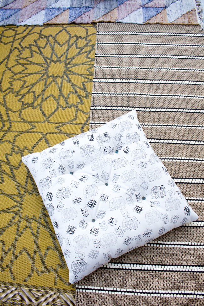 Layered rugs and a stamped outdoor pillow with elephant print